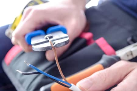 electrician stripping wire ends with wire stripper